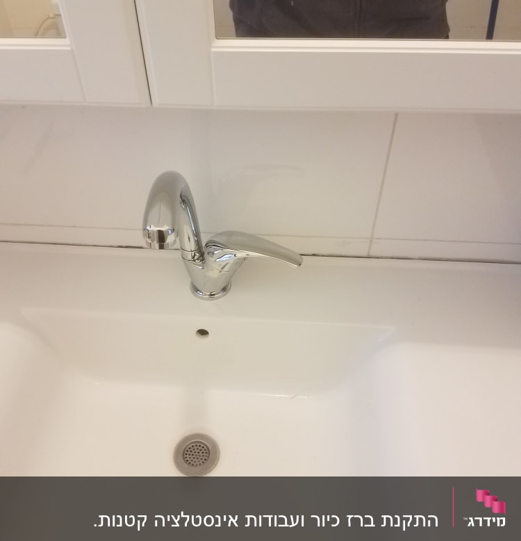 ברז כרום מעל כיור לבן בחדר אמבטיה